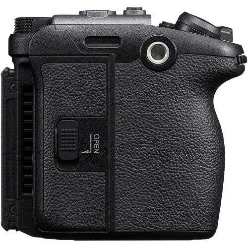 Close-up of the textured black grip and side panel of a camera body, showing a textured leather-like finish, control buttons, and an 'OPEN' switch on a plain white background.