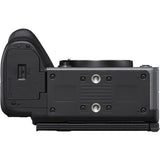 The top-down view of a black mirrorless camera body with an attached vertical grip, showing the textured grip, control buttons, and mounting plate against a white background.