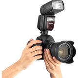 Camera with Godox flash attachment held by a person on a white background