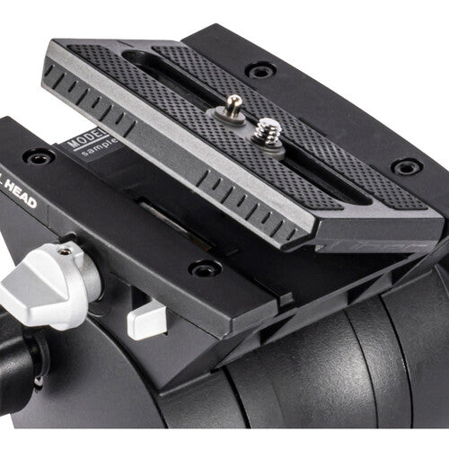 Close-up of a black camera mounting head with a quick-release plate, silver adjustment knobs, and a white release lever on a white background.
