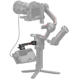 A gimbal camera accessory setup shown on a white background, featuring a camera mounted on a three-legged tripod-style gimbal with an additional monitor mount and cable attached.