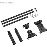 A camera mounting accessory kit laid out on a white background, including three long black tubes, two black handles with red branding, two black mounting brackets, two silver screws, two small black knobs, and two small hex keys. Text in the top left reads 'What's In The Box'.