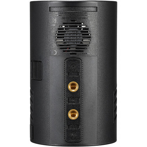 The rear view of a black cylindrical speaker, showing a textured grille, a vented section, and two gold-toned audio input jacks on a plain white background.