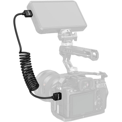 Camera with a mounted light and coiled cable on a white background